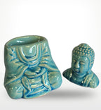 Sitting Buddha Oil Burner - Blue featuring a serene blue resin Buddha figure designed for use as a decorative oil burner with smooth glazed surface and detailed hand-carved style accents.