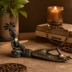 Antique Buddha - Hand Incense Burner featuring a detailed aged bronze hand sculpture holding a small candle, with a seated Buddha figure on the wrist, set in a warm ambient space.