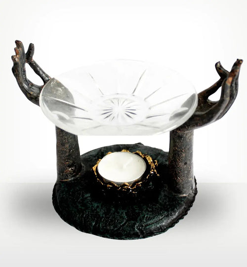 Antique Buddha - Om Hands Oil Burner featuring two sculpted hands in a meditative gesture supporting a glass dish above a tealight candle holder in a rustic dark finish.