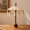 Decorative Bali Home Decor Parasol - Canvas - Gold Decor- 40cm with intricate gold patterns and hanging tassels, displayed on a wooden stand next to candles and glassware.