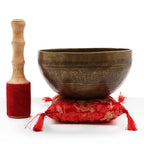 Brass Golden Tara - Special S'Bowl Set featuring a hand-etched brass singing bowl resting on a red decorative cushion with tassels, accompanied by a wooden mallet with a red padded head.