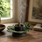 Brass Verdigris Tibetan Cone & Incense Holder - Eight Symbols featuring a lotus-shaped base with intricate detailing, holding a burning incense cone emitting delicate smoke.