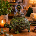 Brass Verdigris Tibetan Turtle Incense Holder - Large emitting fragrant smoke in a cozy room setting with candlelight, plants, and spiritual books in the background.