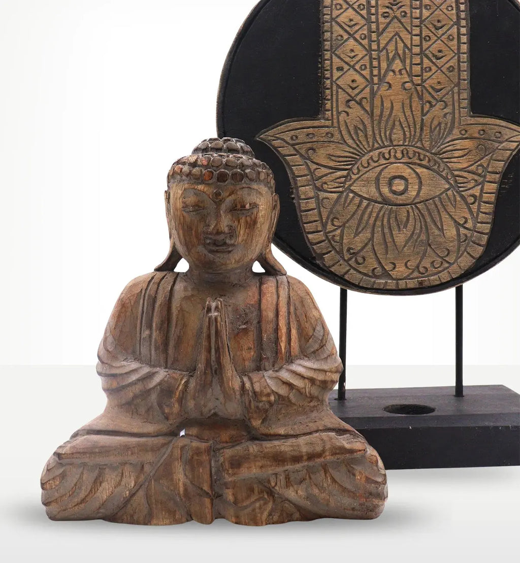 Buddha Feng Shui Set - Hamsa - Grey featuring a hand-carved wooden Buddha statue in a meditative pose with folded hands and a decorative grey Hamsa symbol on a stand in the background.
