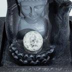 Buddha statue with a crystal ball in its lap on a dark background
