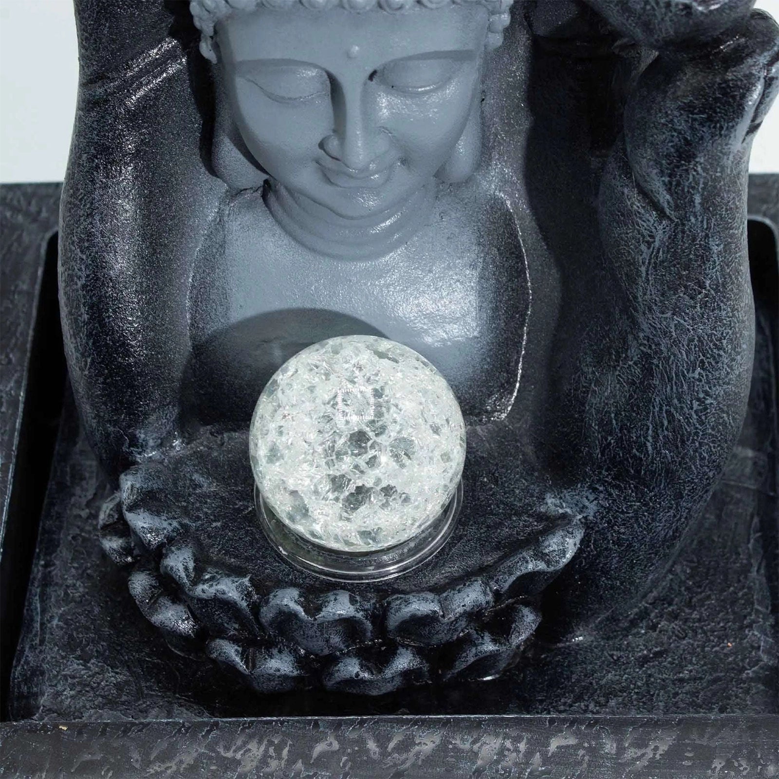 Buddha statue with a crystal ball in its lap on a dark background