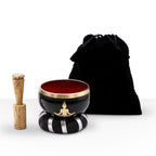 Buddha Singing Bowl Set- Black/Orange 10.7cm featuring a black and orange bowl with a brass Buddha figure design, wooden striker, padded cushion, and black velvet storage pouch.