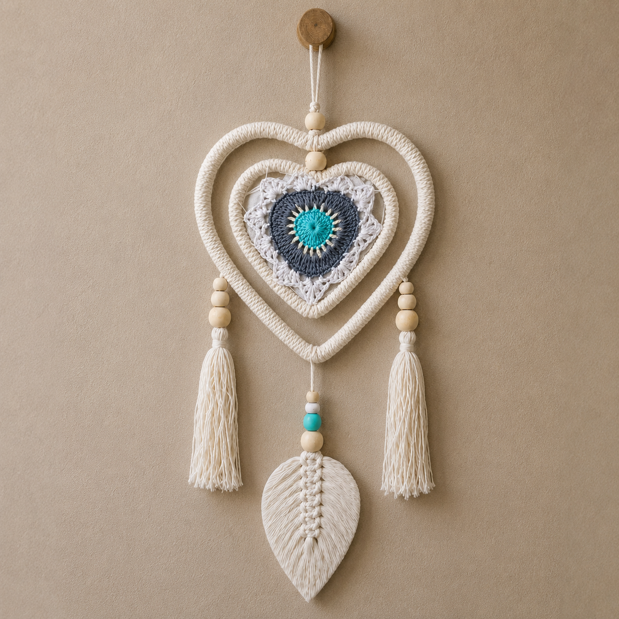 Dream Catcher - Medium Blue Heart in Heart featuring knitted blue and white concentric hearts, beige wooden beads, and white tassels with a leaf-shaped woven charm at the bottom.
