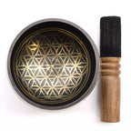 Singing bowl with gold geometric pattern and wooden striker on a white background