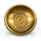 Golden Ganesh Singing Bowl with a detailed embossed figure of Ganesh at the center, showcasing traditional craftsmanship and a smooth polished interior surface.