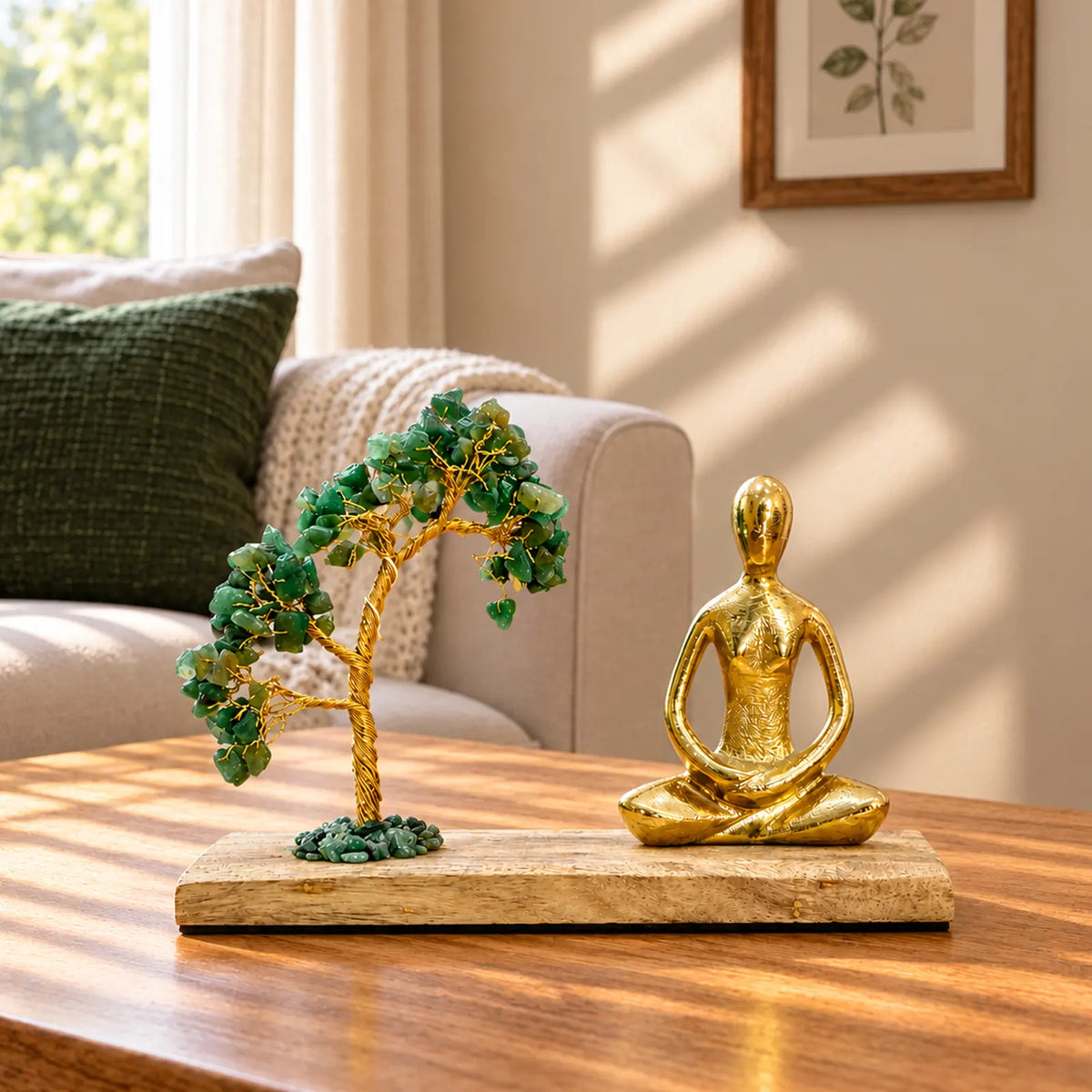 A decorative tabletop set featuring a gold-toned meditating Buddha figurine and a small green gemstone tree on a rectangular wooden base, placed on a wooden table in a sunlit living room.