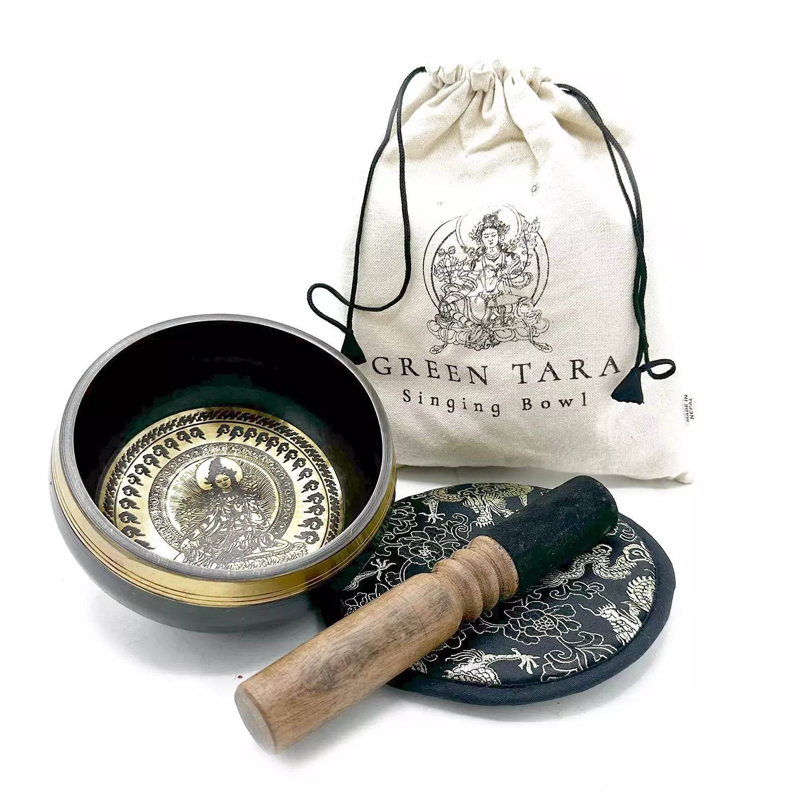 Singing bowl set with decorative plate and cleaning stick, accompanied by a 'Green Tara' branded bag on a white background.