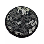 Black circular mat with white floral and dragon designs on a white background