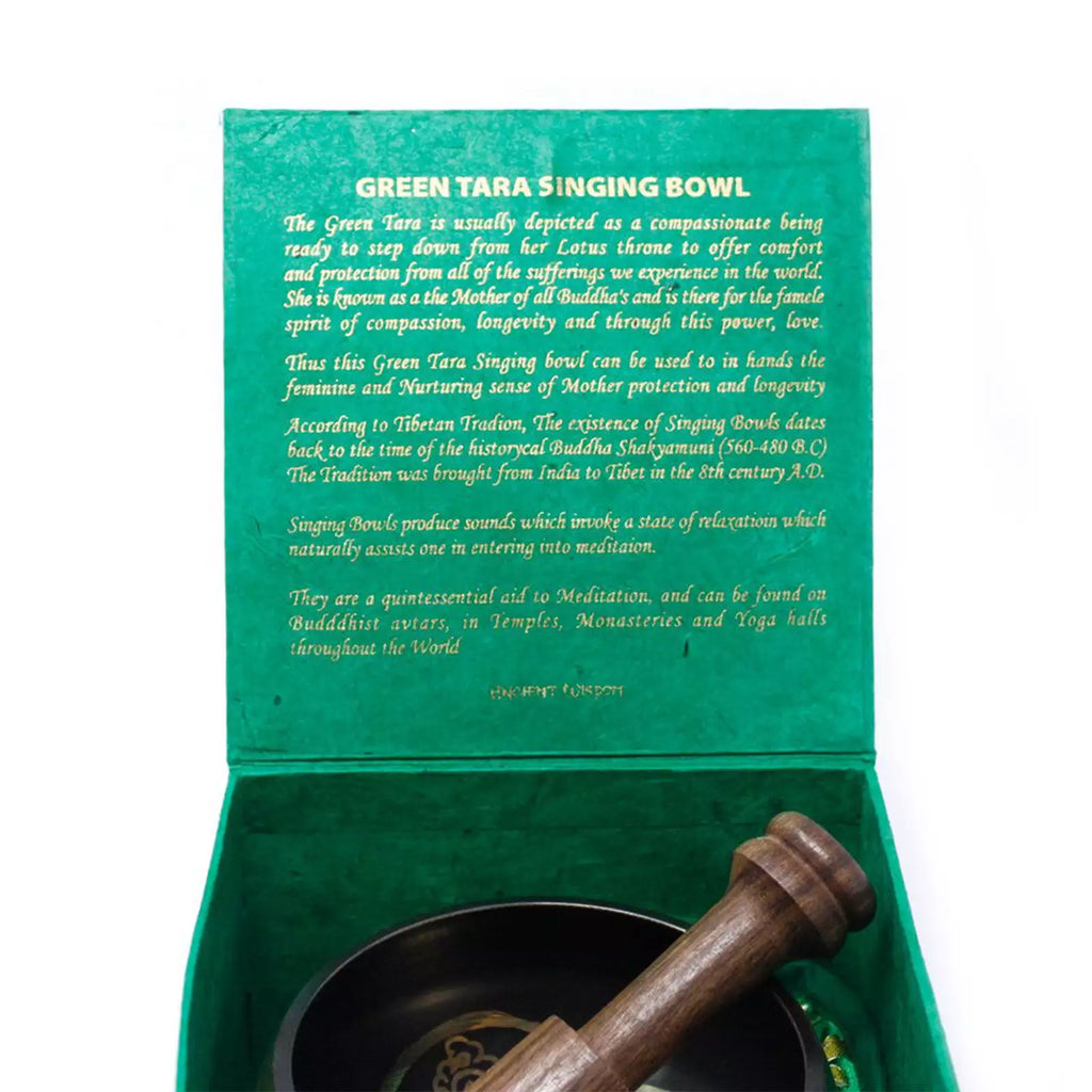 Open green presentation box containing a dark green singing bowl and a wooden mallet, with printed text on the inner lid describing the Green Tara singing bowl.
