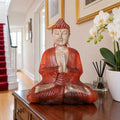 40 cm wooden Buddha with hands in prayer on a dark hall cabinet beside a red-carpeted staircase.