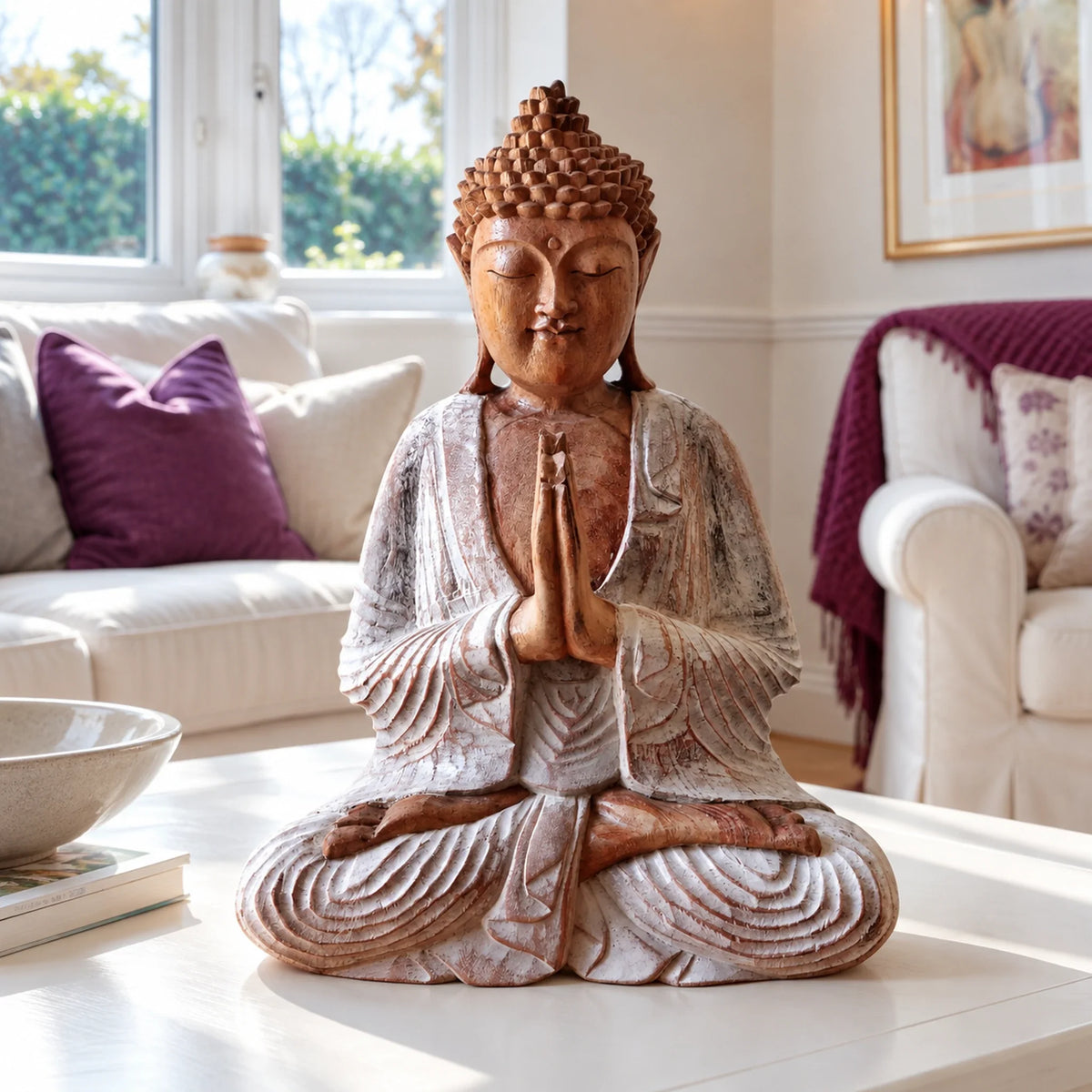 30 cm whitewashed wooden Buddha seated in prayer on a white coffee table, with purple cushions behind.