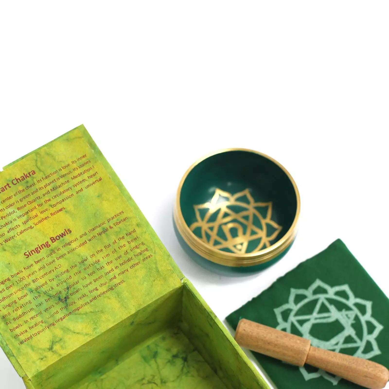 Green singing bowl with gold design, wooden stick, and green box on a white background