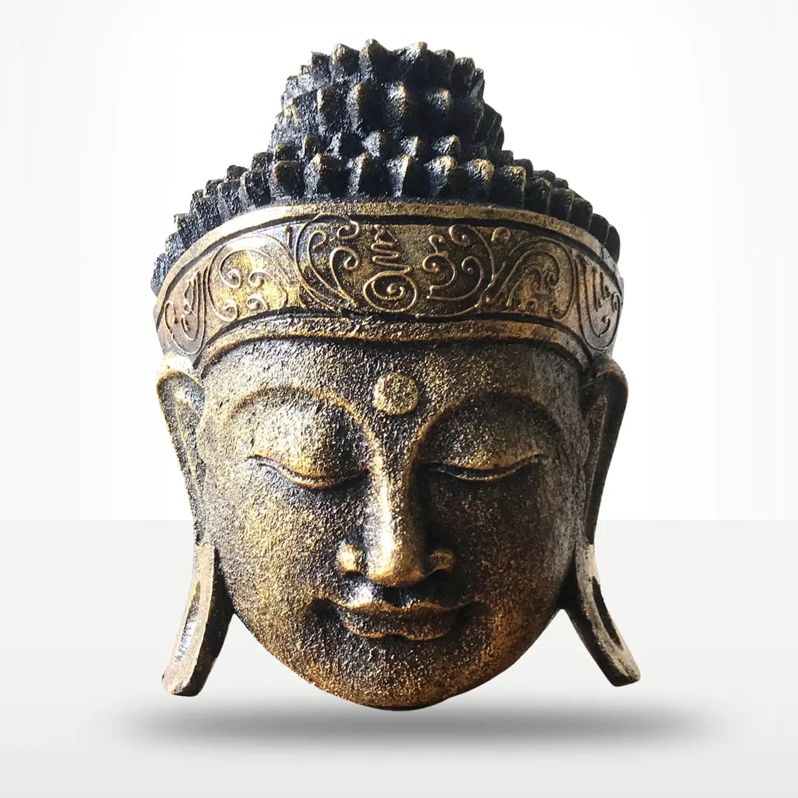 A bronze-finished Buddha head sculpture with closed eyes, ornate hair detail, and a decorative headband, shown against a light gray background.