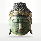 A decorative Buddha head sculpture with a textured, weathered finish in greenish-bronze tones and gold accents on the crown band, shown against a light gray gradient background.