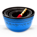 Large Chakra Set of Seven Singing Bowls (19.5-35cm) nested together with a wooden mallet featuring Tibetan script and decorative patterns on the blue exterior.