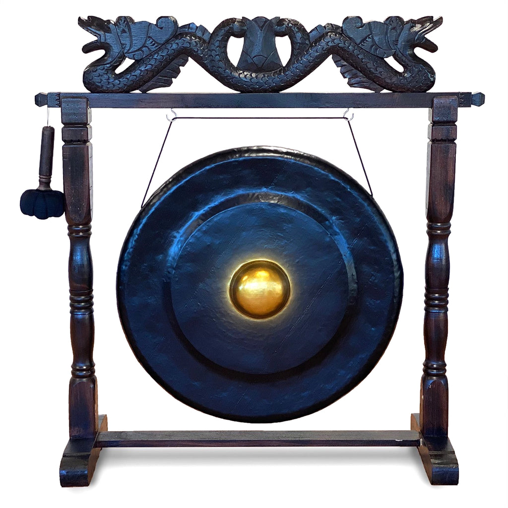A large dark blue gong with a polished gold center, mounted on a dark wooden stand with carved dragon details at the top and a hanging mallet on the left, shown on a plain white background.