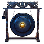 A large dark blue gong with a polished gold center, mounted on a dark wooden stand with carved dragon details at the top and a hanging mallet on the left, shown on a plain white background.