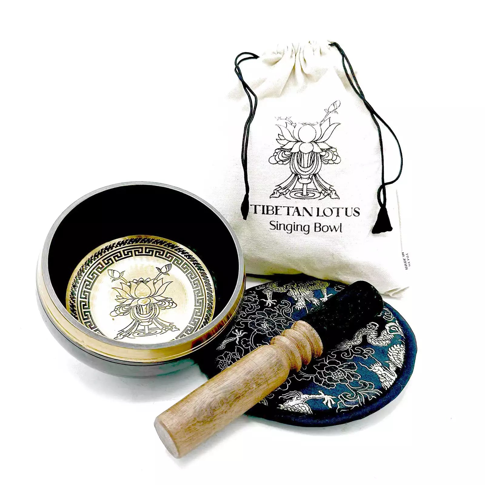 Tibetan singing bowl set with lid, cushion, and mallet on a white background