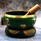 Large Tree of Life Singing Bowl Set- Green 14cm featuring a green bowl with gold om symbols, a wooden striker, and a decorative cushion for sound meditation and relaxation.