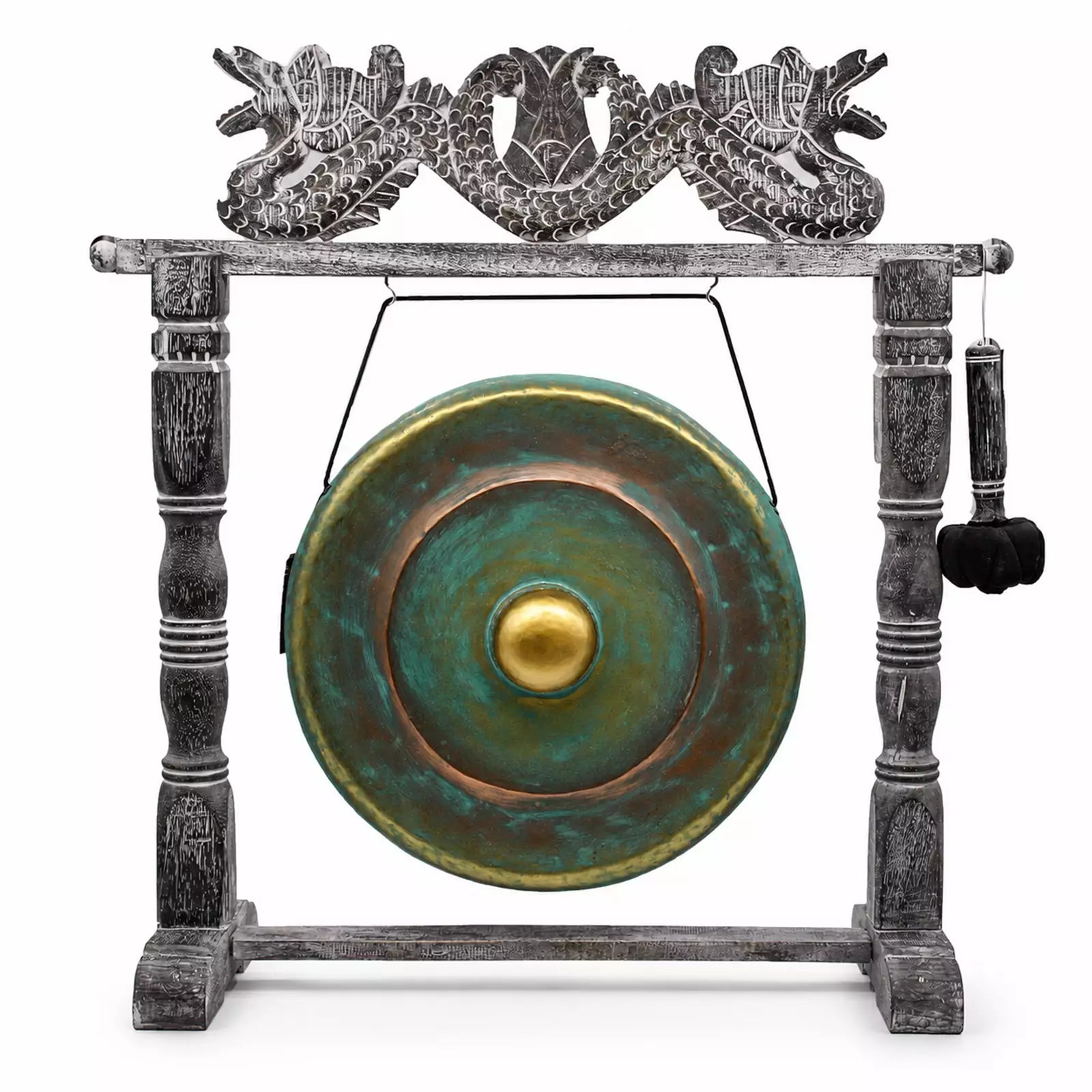 A decorative gong set on a carved stand, featuring a round green and bronze gong with a gold center, suspended by a wire from a weathered gray wooden frame topped with a dragon motif, and a hanging mallet on the right.