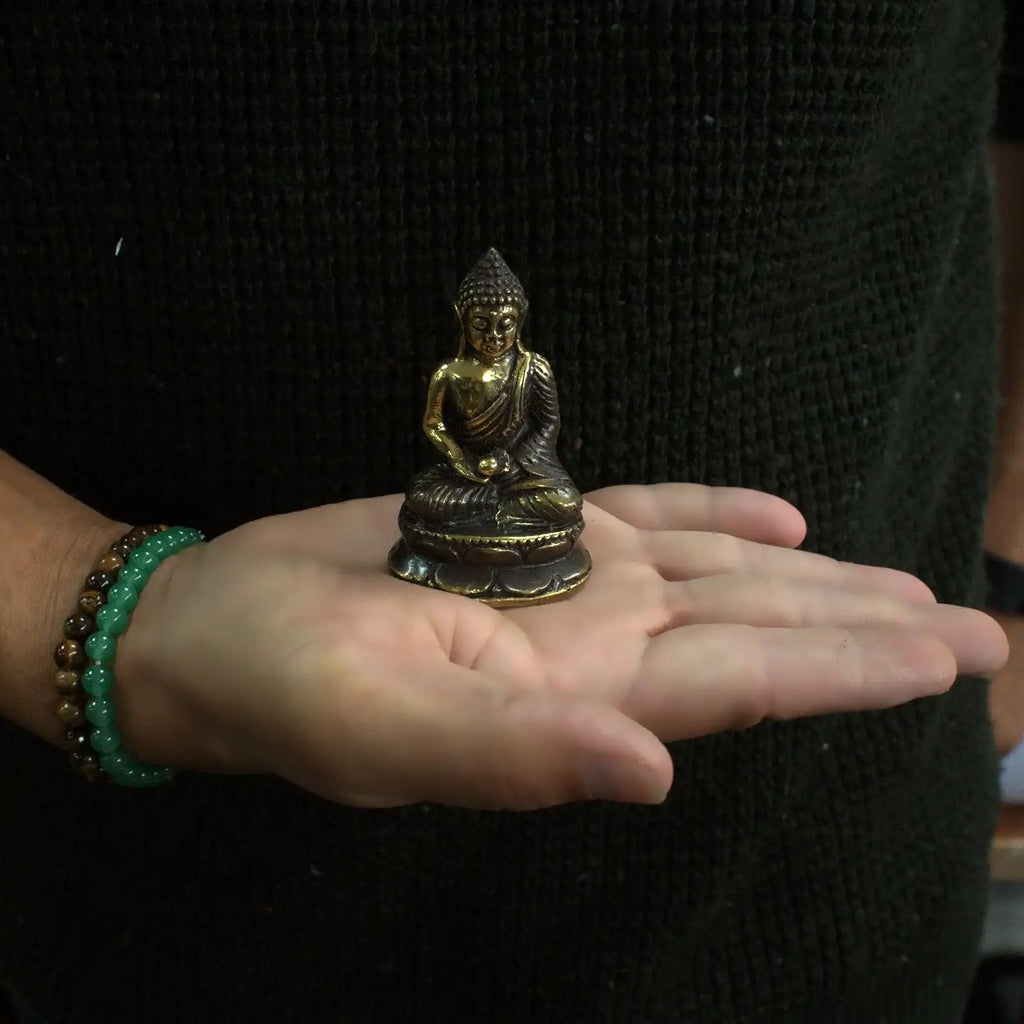 Mini Meditating Sitting Buddha statue in brass finish held in an open hand, showcasing its detailed craftsmanship and compact size for Buddha decor.