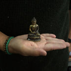 Mini Meditating Sitting Buddha statue in brass finish held in an open hand, showcasing its detailed craftsmanship and compact size for Buddha decor.