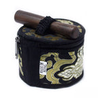 A small black zippered fabric case with ornate gold embroidered patterns, shown on a white background. A dark wooden mallet rests across the top, secured by a black elastic band.