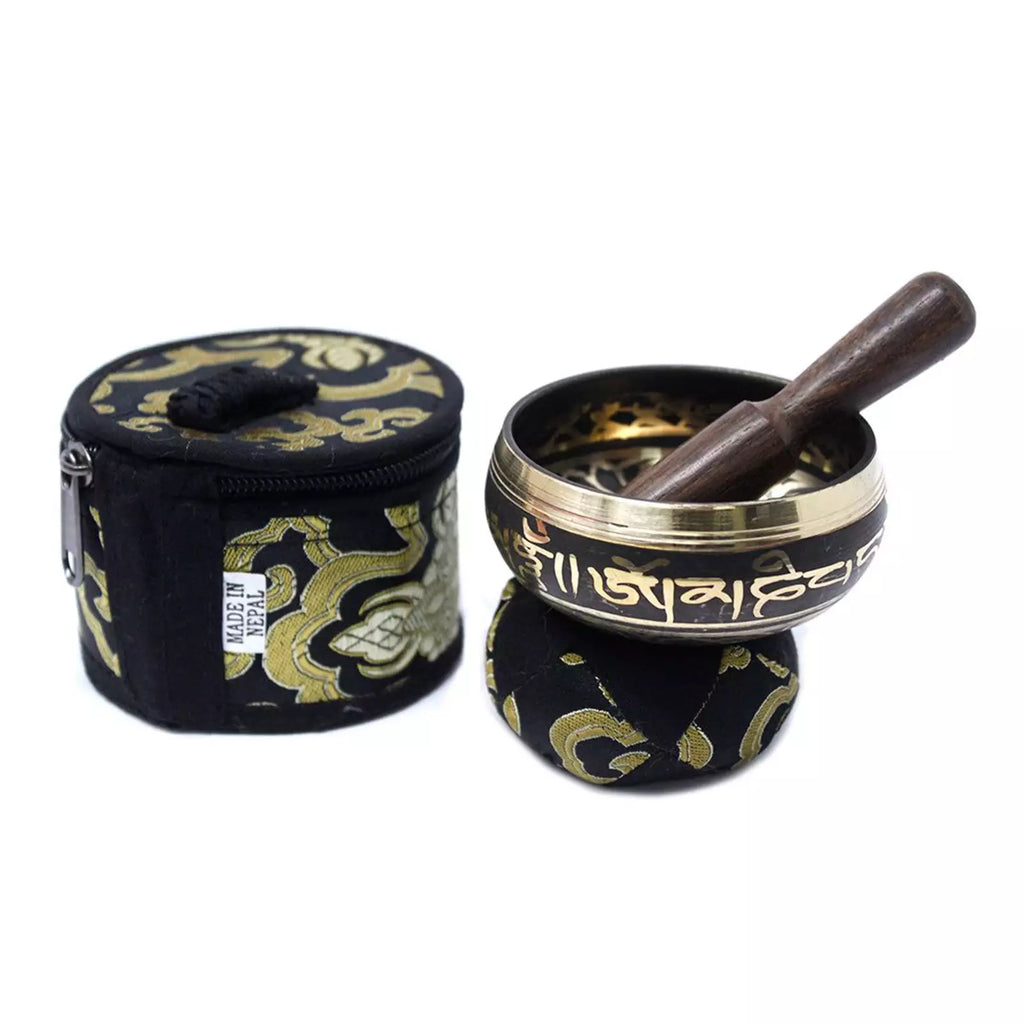 A Tibetan singing bowl set with a wooden mallet and a black fabric carrying case decorated with gold patterns and Tibetan script, shown on a white background.