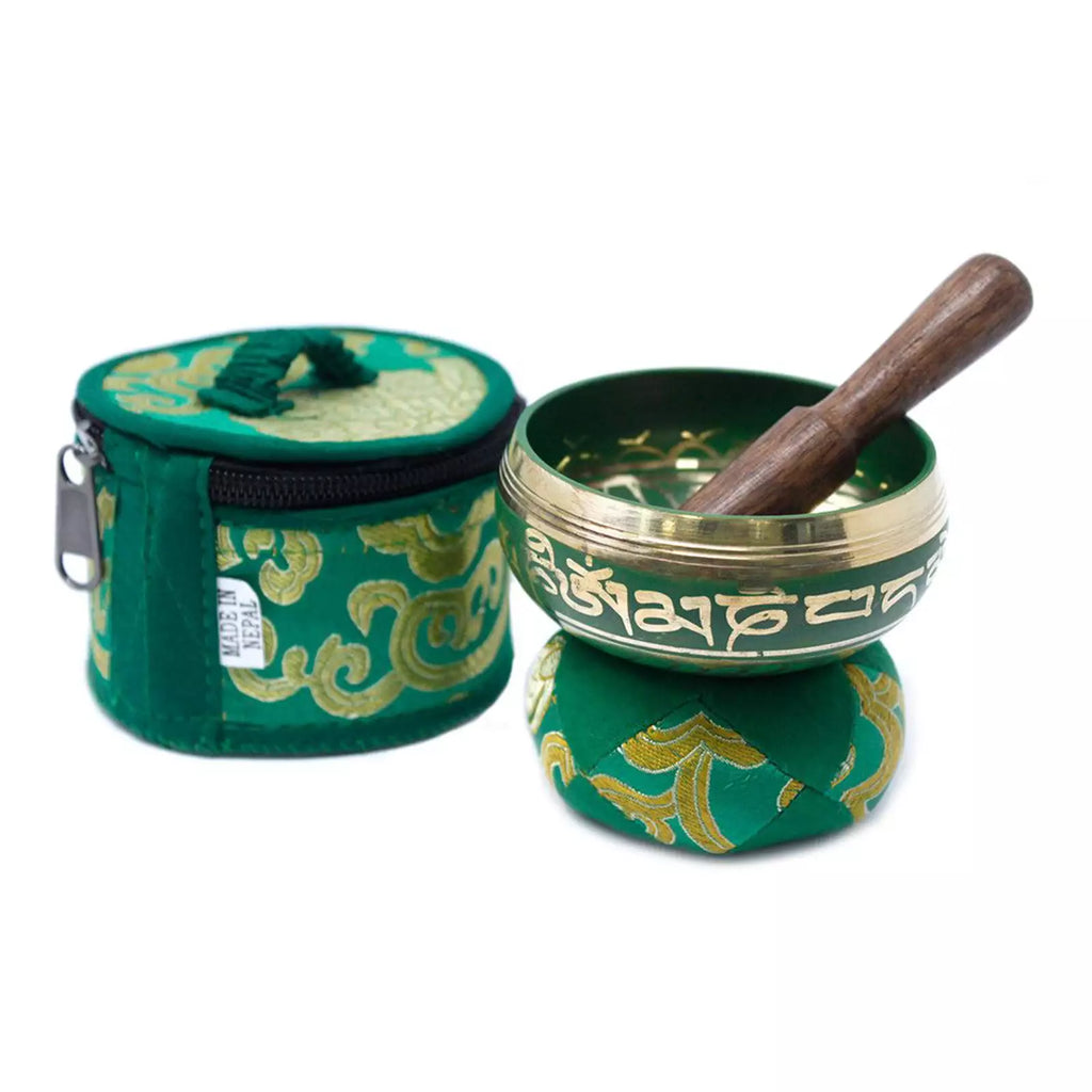 A Tibetan singing bowl set with a green and gold patterned fabric case, an open singing bowl with white script, and a wooden mallet on a white background.