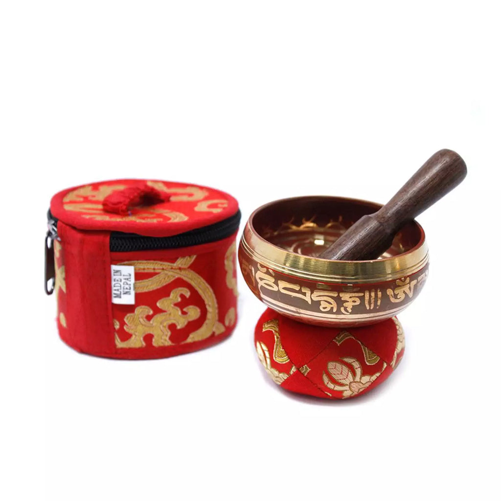 A Tibetan singing bowl set with a bronze singing bowl, wooden striker, and a red zippered fabric carrying case with gold decorative patterns, shown on a white background.