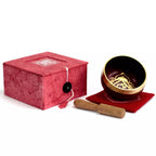 Singing bowl set with red box and wooden striker on a white background