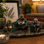 Set of 3 - Happy Buddha's (asst sizes) hand-carved resin statues with antique brass finish, displayed on a marble tray with cozy home decor background.