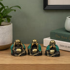 Set of 3 - See No Evil etc - Buddha statues in antique gold and green finish, featuring hand-carved resin figures depicting the classic see no evil poses on a wooden surface with books and plants nearby.