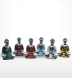 A row of six Silver Mini Buddha (Assorted Colours) statues in green, red, orange, blue, silver, and gold, designed as small Buddha decor pieces with a serene seated pose.