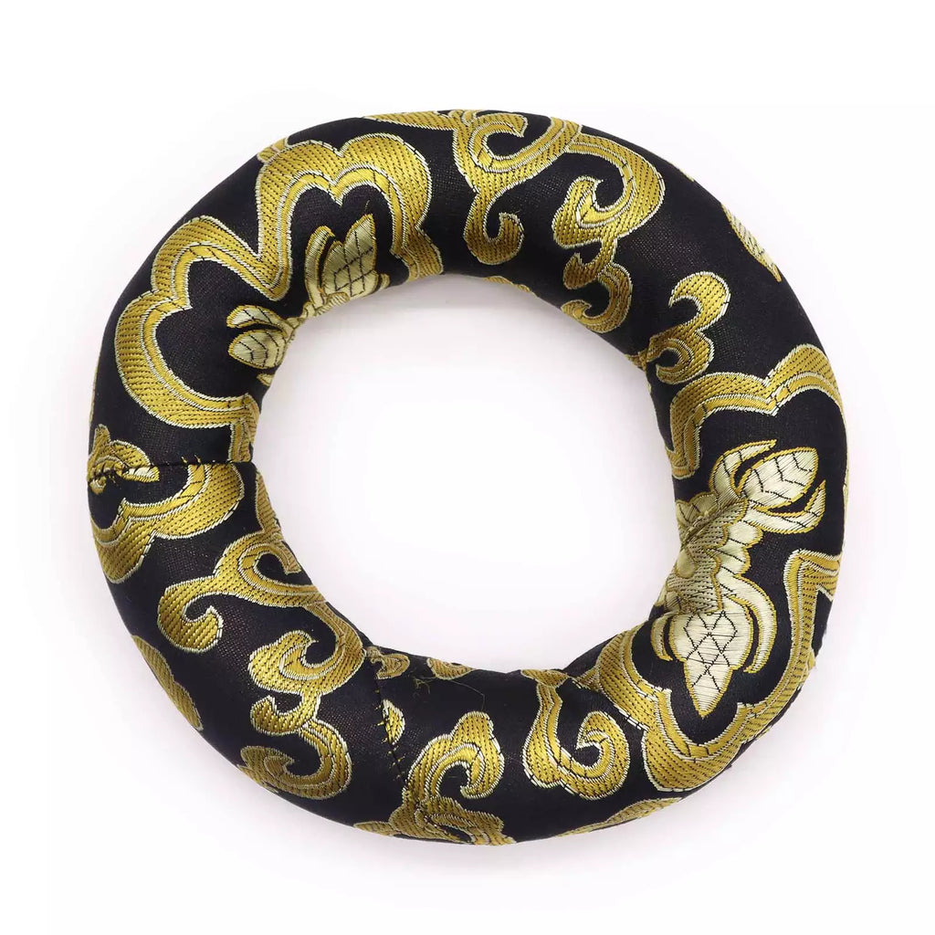 A padded circular ring cushion with a black fabric base and an ornate gold damask pattern, shown on a plain white background.