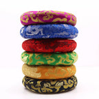 A stack of seven round woven cushions in vibrant colors, each featuring traditional Chinese dragon and cloud patterns in gold brocade fabric. The cushions are stacked vertically on a clean white background, showing a variety of base colors including magenta, blue, red, green, orange, and black.