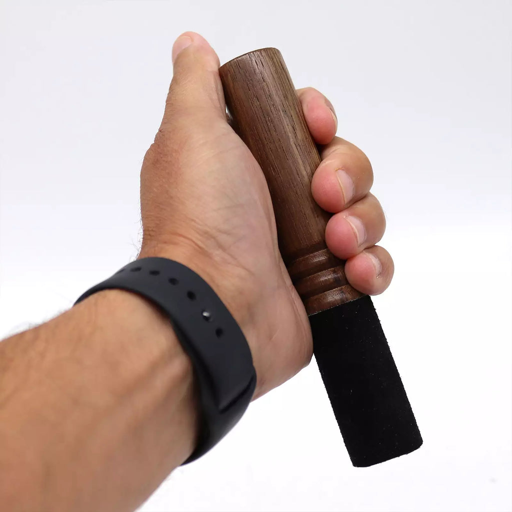 Hand holding a wooden object with a black handle against a white background