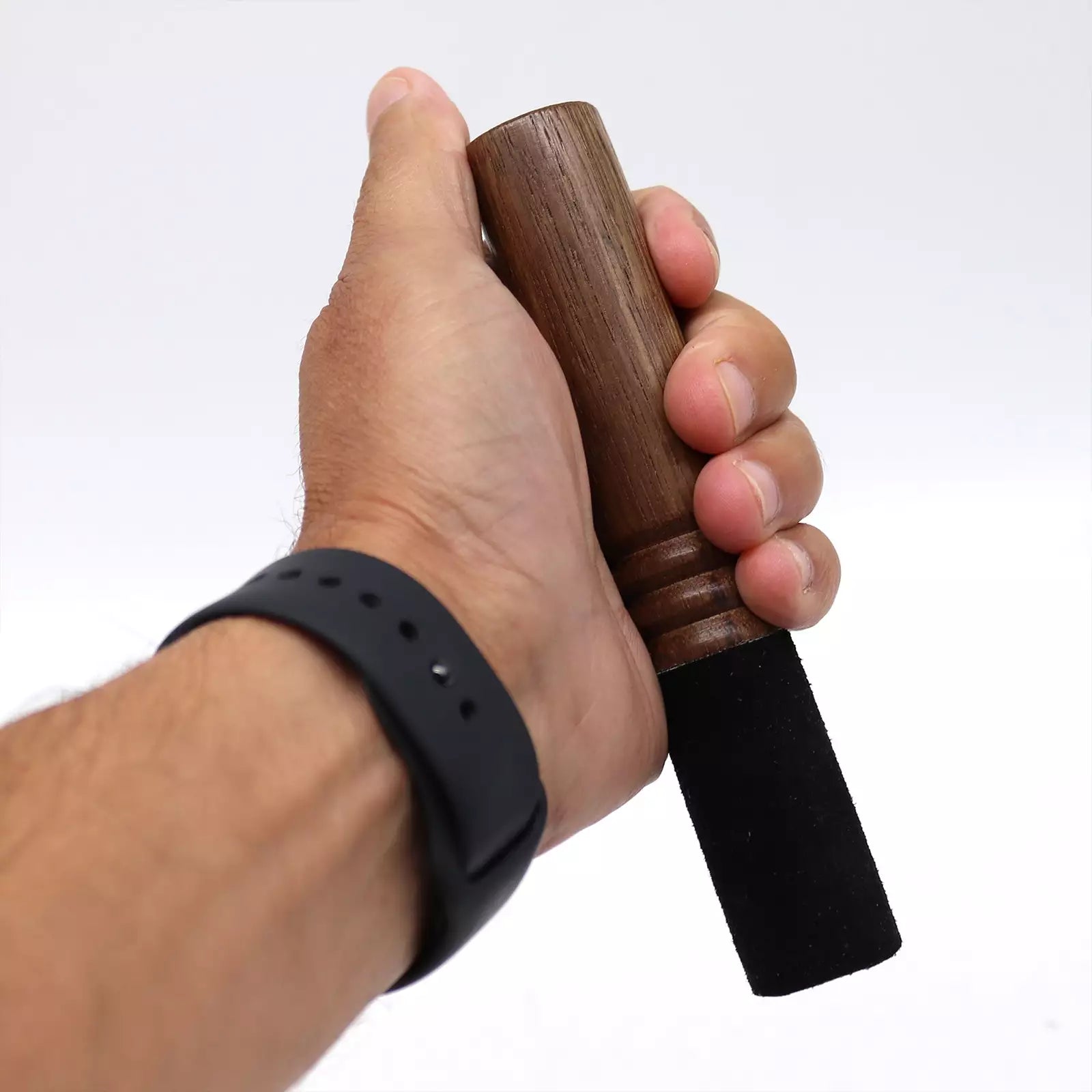 Hand holding a wooden object with a black handle against a white background