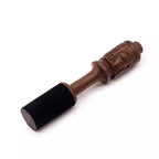 A wooden massage tool with a carved tiki-style head and a black velvet-covered cylindrical handle, shown on a plain white background.