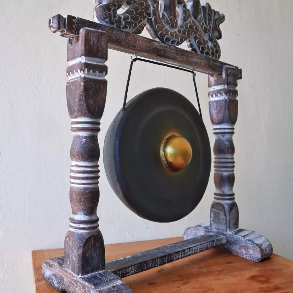 Traditional gong on a wooden stand against a plain wall