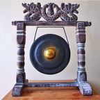 Decorative gong with wooden stand on a plain background