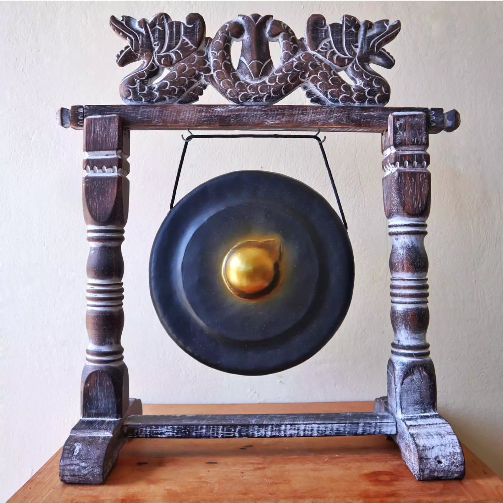 Decorative gong with wooden stand on a plain background