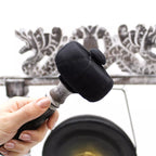 Person holding a black and gray cleaning tool against a decorative wall.