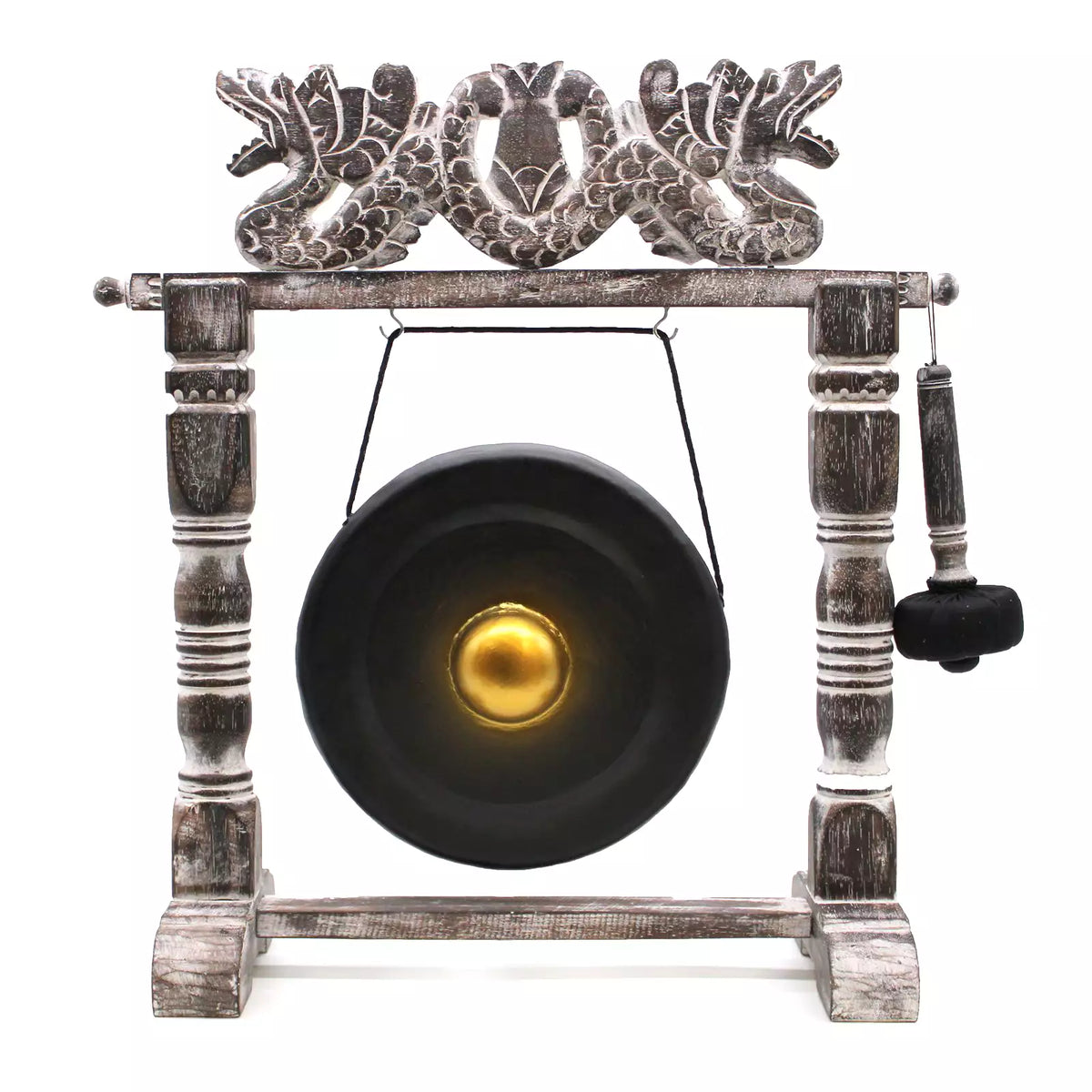 A decorative hanging gong set on a weathered wooden stand with ornate dragon-like carvings at the top, a black gong with a gold center, and a hanging mallet on a white background.