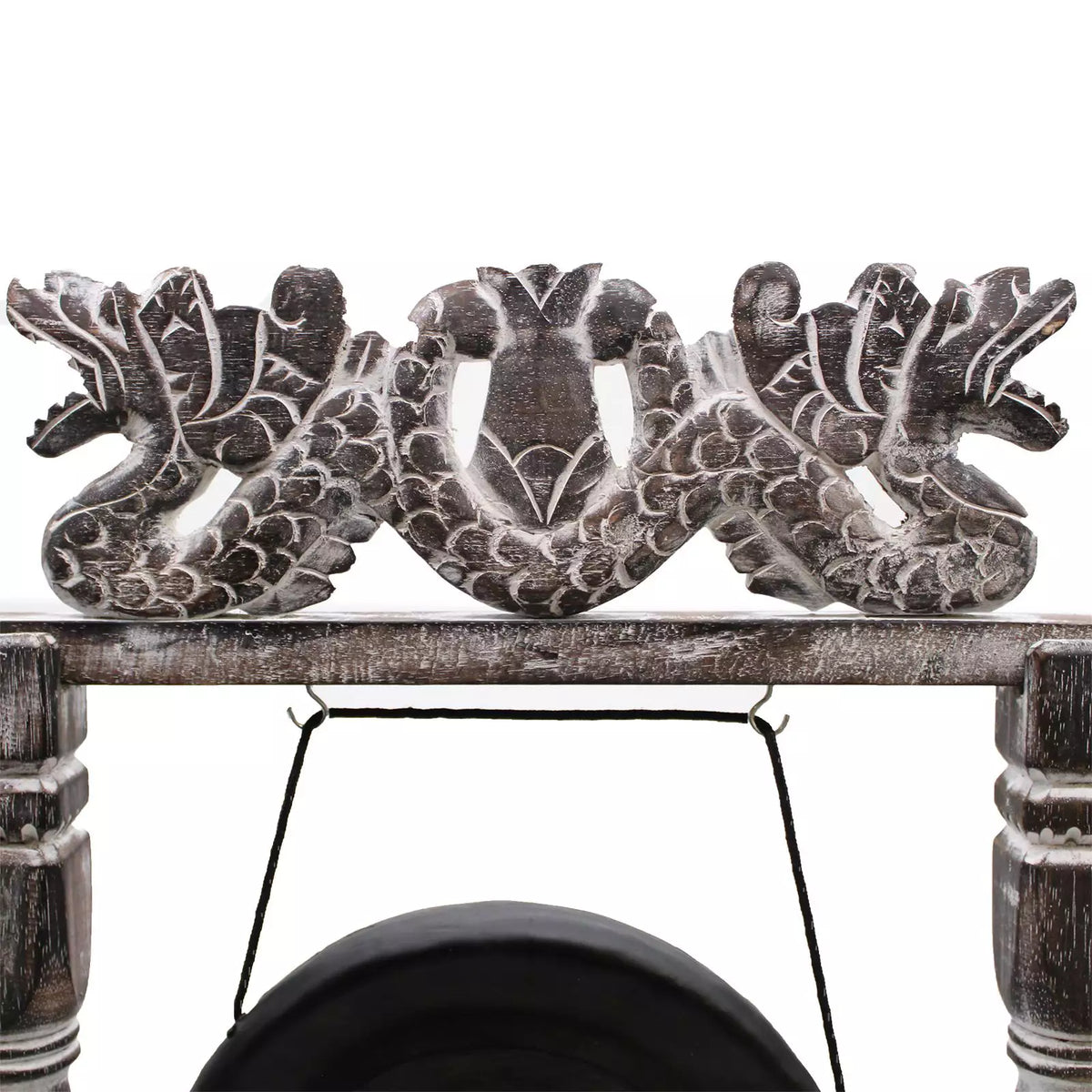 A close-up of a carved wooden decorative piece featuring two dragon figures flanking a central motif, mounted on a rustic wooden beam with a hanging black cord below.